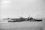 HM Ships Birmingham, Formidable, Warspite and Illustrious seen from HMS Mauritius, July 1942. A number of naval aircraft can be seen on the flight deck of the nearer carrier, ready to take off. Imperial War Museums A 13455
