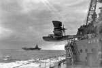 The Supermarine Walrus amphibious aircraft from HMS Warspite is catapulted from the ship at the start of an anti-submarine patrol off the Seychelles in the Indian Ocean during WWII. An aircraft carrier can be seen sailing in the background. Photo: Lt. D. C. Ouids. Imperial War Museums A 11027