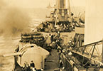 HMNZS Gambia firing a broadside of 4" and 2lb guns off of Japan in 1945. HMS Howe can be seen in the background. From original site, NMRNZN - AAI0065